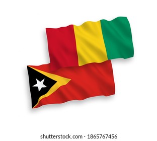 National vector fabric wave flags of East Timor and Guinea isolated on white background. 1 to 2 proportion.