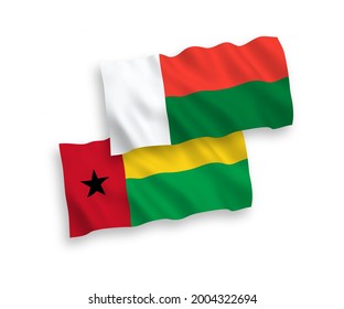 National vector fabric wave flags of Republic of Guinea Bissau and Madagascar isolated on white background. 1 to 2 proportion.
