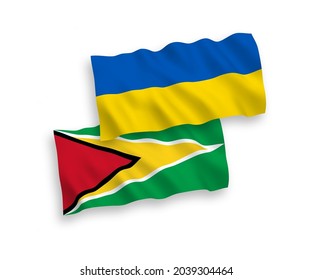 National vector fabric wave flags of Co-operative Republic of Guyana and Ukraine isolated on white background. 1 to 2 proportion.