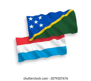 National vector fabric wave flags of Solomon Islands and Luxembourg isolated on white background. 1 to 2 proportion.