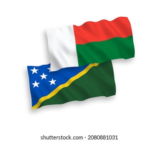 National vector fabric wave flags of Solomon Islands and Madagascar isolated on white background. 1 to 2 proportion.