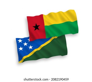 National vector fabric wave flags of Solomon Islands and Republic of Guinea Bissau isolated on white background. 1 to 2 proportion.