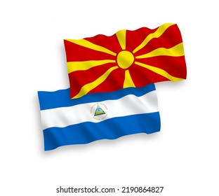 National vector fabric wave flags of Nicaragua and North Macedonia isolated on white background. 1 to 2 proportion.