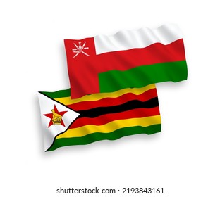 National vector fabric wave flags of Sultanate of Oman and Zimbabwe isolated on white background. 1 to 2 proportion.