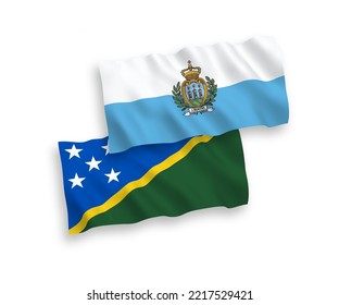 National vector fabric wave flags of San Marino and Solomon Islands isolated on white background. 1 to 2 proportion.