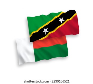 National vector fabric wave flags of Federation of Saint Christopher and Nevis and Madagascar isolated on white background. 1 to 2 proportion.