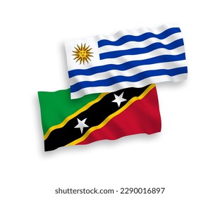 National vector fabric wave flags of Oriental Republic of Uruguay and Federation of Saint Christopher and Nevis isolated on white background. 1 to 2 proportion.