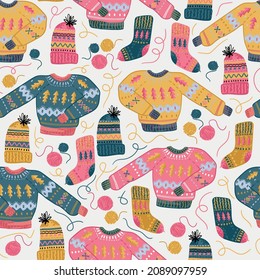 Needlework seamless pattern with sweater, knitting hat, sock and woolen tangles. Hand made clothes.