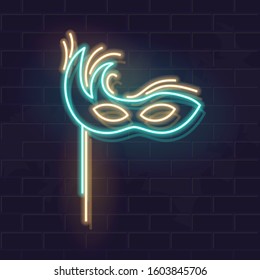 Neon asymmetric carnival mask. Decorated, fashioned masquerade accessory. Fluorescent icon on brick wall background. Square vector illustration for social network, logo, poster.