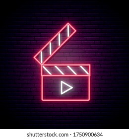 Neon clapperboard sign. Bright glowing clapperboard on dark brick wall background. Cinema emblem. Vector design template.