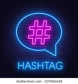 Neon hashtag sign in speech bubble on brick wall background.
