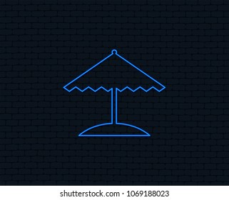Neon light. Beach umbrella sign icon. Protection from the sun. Glowing graphic design. Brick wall. Vector