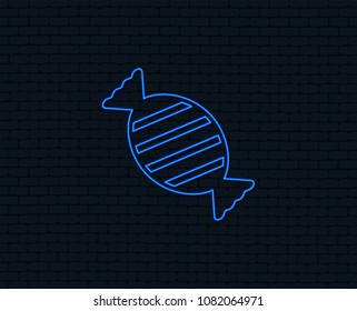 Neon light. Candy icon. Sweet food sign. Glowing graphic design. Brick wall. Vector