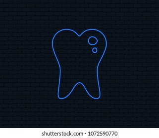 Neon light. Caries tooth icon. Tooth filling sign. Dental care symbol. Glowing graphic design. Brick wall. Vector