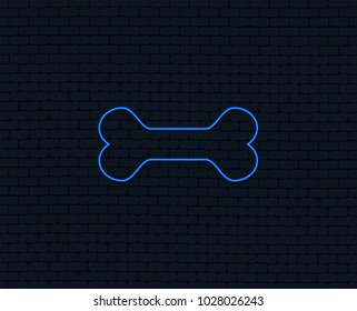 Neon light. Dog bone sign icon. Pets food symbol. Glowing graphic design. Brick wall. Vector
