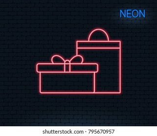 Neon light. Gift box with bag line icon. Present or Sale sign. Birthday Shopping symbol. Package in Gift Wrap. Glowing graphic design. Brick wall. Vector