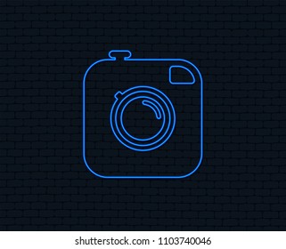 Neon light. Hipster photo camera sign icon. Retro camera symbol. Glowing graphic design. Brick wall. Vector