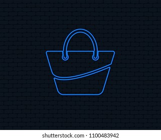 Neon light. Woman bag icon. Female handbag sign. Glamour casual baggage symbol. Glowing graphic design. Brick wall. Vector