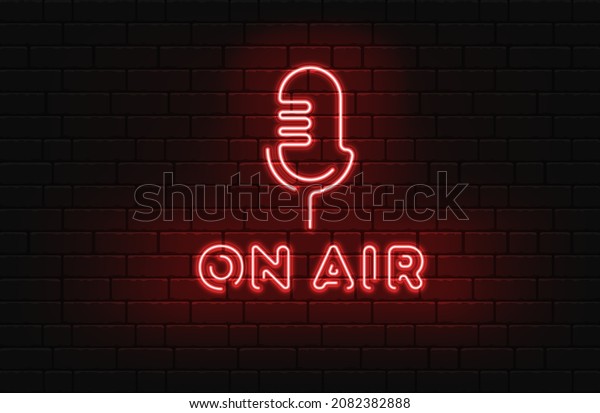 Neon on the air sign with retro microphone on\
dark brick wall\
background.