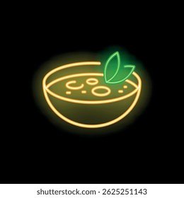 Neon sign of a bowl of soup with leaves is glowing on a black background