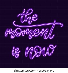 Neon sign the moment is now calligraphic lettering vector illustration with calligraphy style word. Handwritten text for fabric print, poster, card. Light banner, glowing neon signboard.