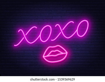 Neon sign xoxo with a kiss on a dark background.