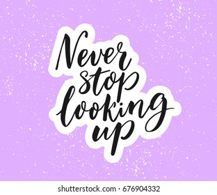 Never stop looking up. Inspirational quote, brush calligraphy on purple background