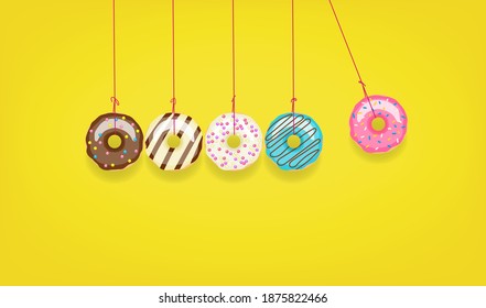 Newton's cradle from doughnuts. Collision balls made from donuts. Harm of sugar, donuts time or healthy diet concept. Dependence on flavoring, diabetes problems, weight loss.