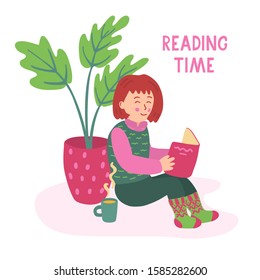 A nice little girl sitting on the floor and reading a book. There is a mug of tea and an indoors plant near her. Reading time lettering. Vector illustration isolated on white background.