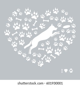 Nice picture of jumping dog silhouette on a background of dog tracks and bones in the form of heart on a colored background.