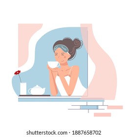 Buena joven tomando té en una ventana. Una chica linda con una máscara de sueño en su cabeza disfrutó la mañana.