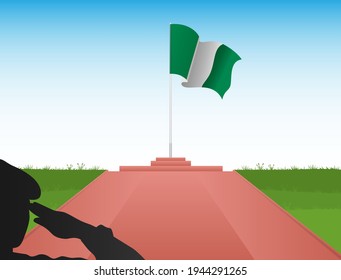 The Nigerian flag flies above the pole in the shadow of a soldier saluting the flag