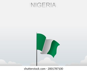 Nigerian flag flying on a pole standing tall under a white sky