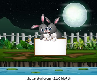 Night landscape with bunnies cartoon holding blank sign by the lake