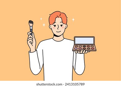 Non-binary man applies makeup and skin shadow, holding mirror and brush to apply powder. Non-binary guy uses cosmetics, wanting to become like girl, for concept of gender identity and tolerance