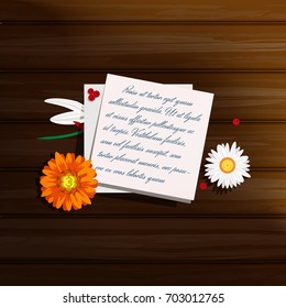 A note on a wooden table with beautiful flowers (Chammomile, marigold) and berries 
