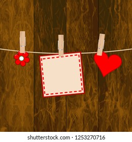 Note paper, flower and heart on the wooden background with clothespins
