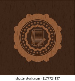 notebook with pencil icon inside badge with wooden background