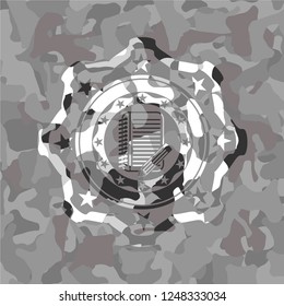 notebook with pencil icon inside grey camo emblem