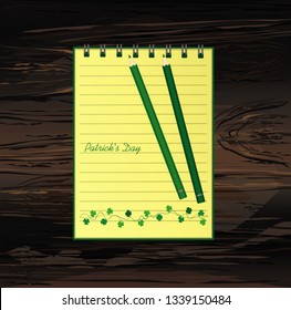 Notebook with template hand-drawn Green festive bunting with clover and pencil. Irish holiday - Happy St. Patrick's Day with a garland of three-leaf. Vector on wooden background
