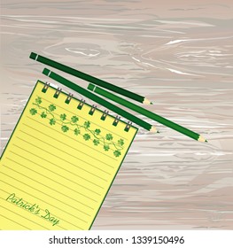 Notebook with template hand-drawn Green festive bunting with clover and pencil. Irish holiday - Happy St. Patrick's Day with a garland of three-leaf. Vector on wooden background