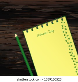 Notebook with template hand-drawn Green festive bunting with clover and pencil. Irish holiday - Happy St. Patrick's Day with a garland of three-leaf. Vector on wooden background