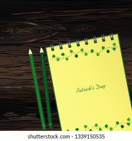 Notebook with template hand-drawn Green festive bunting with clover and pencil. Irish holiday - Happy St. Patrick's Day with a garland of three-leaf. Vector on wooden background
