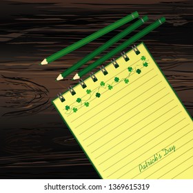 Notebook with template hand-drawn Green festive bunting with clover and pencil. Irish holiday - Happy St. Patrick's Day with a garland of three-leaf. Vector on wooden background