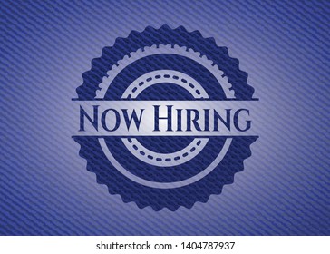 Now Hiring emblem with jean texture. Vector Illustration. Detailed.
