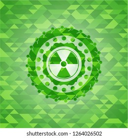 nuclear, radioactive icon inside green emblem with triangle mosaic background