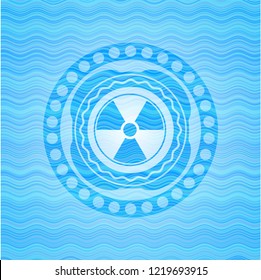 nuclear, radioactive icon inside sky blue water wave badge.