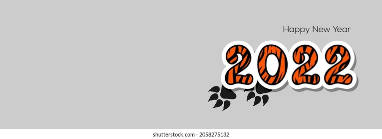 Number 2022 with orange and black tiger print and tiger tracks on a gray background with copy space. Happy New Year 2022 banner