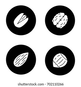 Nuts types glyph icons set. Pistachio, walnut, almond, hazelnut. Vector white silhouettes illustrations in black circles