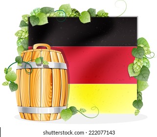 Oak wooden beer barrel on the background of the German flag, decorated with green hops